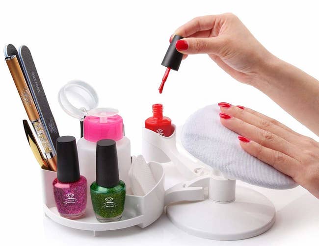 A person using the nail design pedestal to paint their nails. 