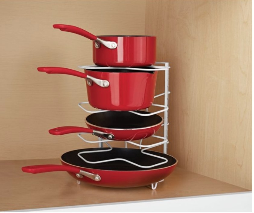 A white wire framed organizing rack holding red pots and pans