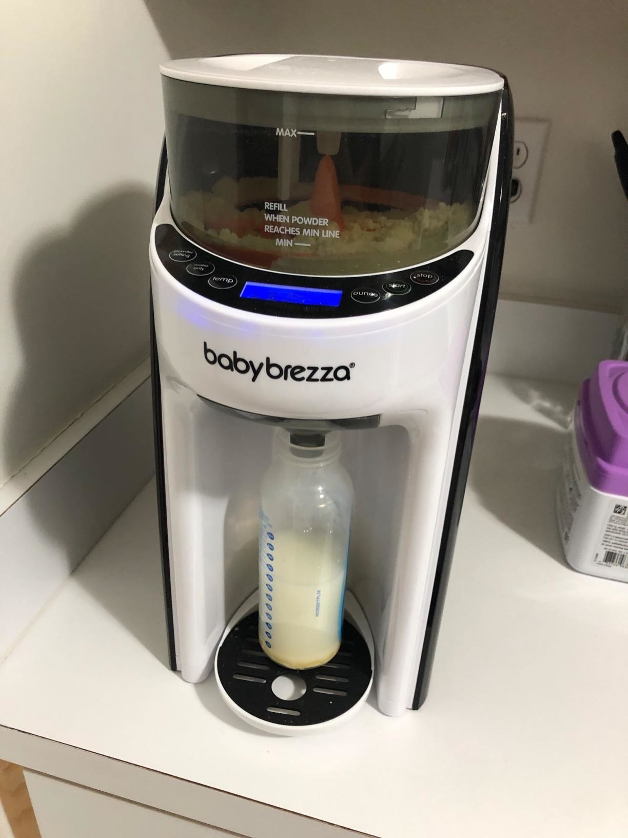 reviewer&#x27;s photo of the formula dispenser filling a bottle 
