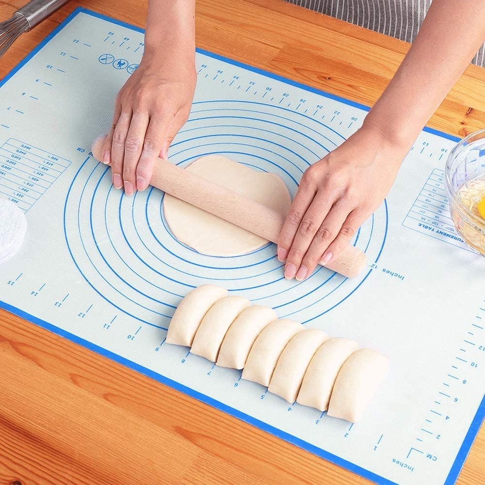 A person rolling out dough on a silicone pastry mat