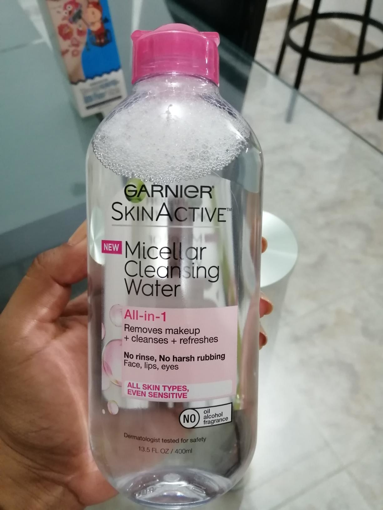 Reviewer holding the bottle of makeup remover 