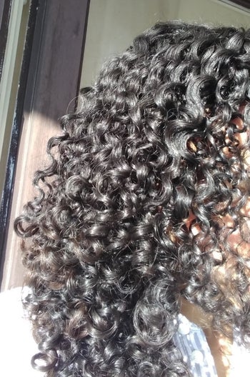 Reviewer with tight curls showing the product adds shine