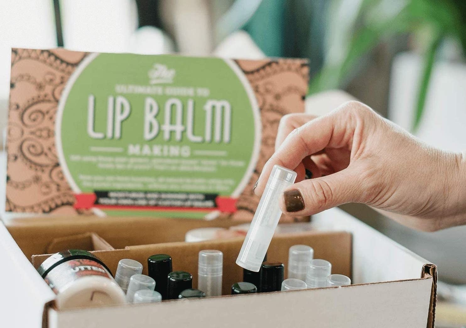 A hand removes a tube from the balm making kit