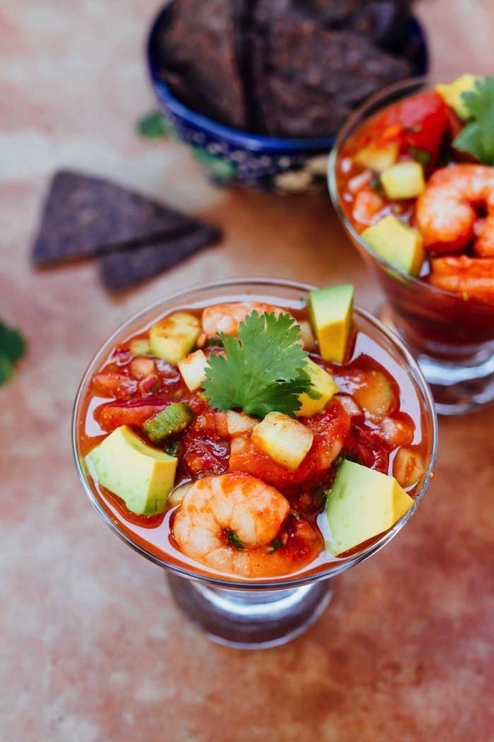 A dish with shrimp and avocado in a tomato sauce.