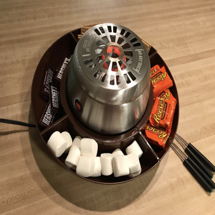 Reviewer image of the s'mores maker with marshmallows, Reese's, and graham crackers in its holding spots 