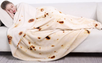 A model sleeping in a blanket that looks like a tortilla wrap 