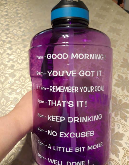 Reviewer photo of BuildLife motivational water bottle in purple, featuring time markers from 7am-9pm so you always know how much more water you have left to drink in the day and can easily pace yourself 