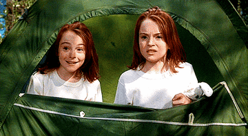 GIF of the twin sisters in a tent together grimacing at something they see that&#x27;s not shown