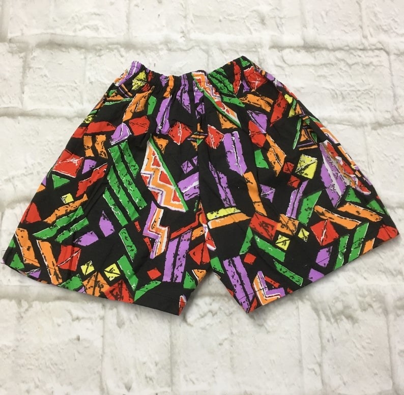 A pair of black shorts with different colored prints on it. 