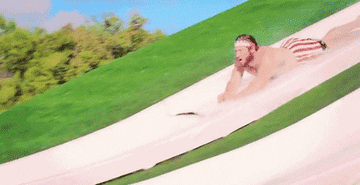 A man flying off a water slide and pulling his 