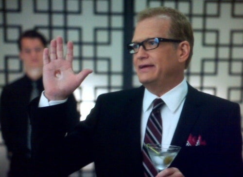 Drew Carey holds a martini in one hand while his other hand has a hole in it