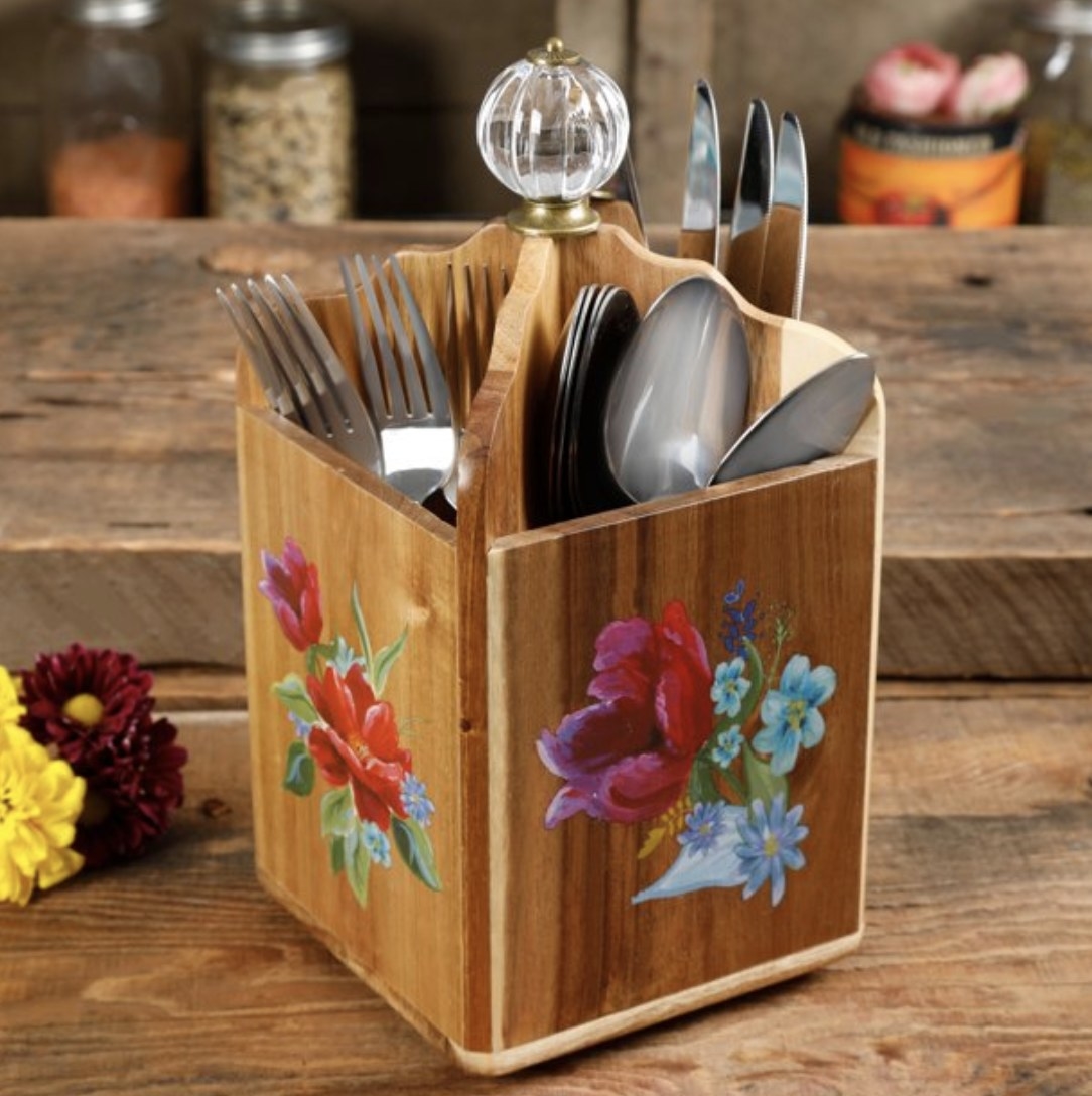 The wooden utensil holder with four sections for different cutlery and a painted floral design 