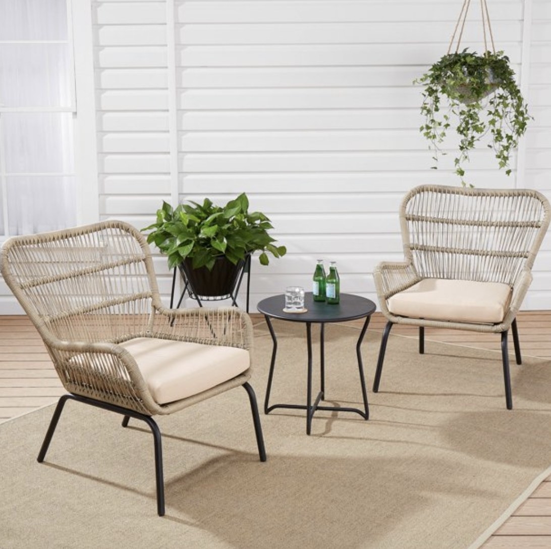 The patio set with light wooden wicker chairs and a round black side table  