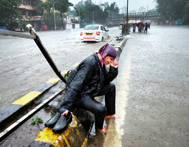 A man cries while sitting on the divider of a water-logged street of Mumbai and the rain keeps pouring