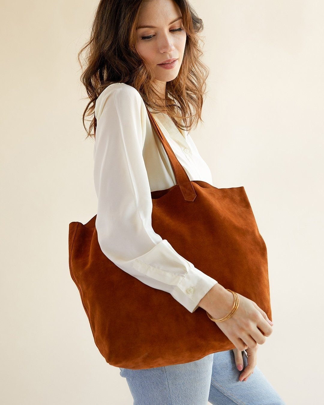 A model carrying a brown suede tote