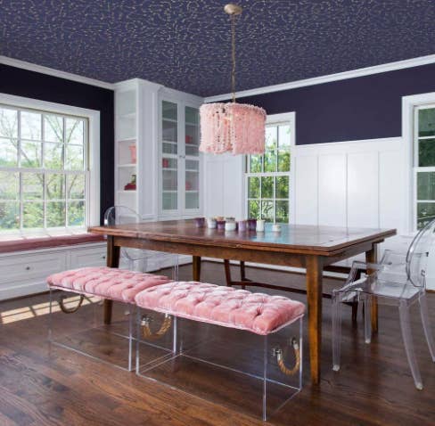 Navy blue removable wallpaper with a constellation print above a wood dining table and plush velvet benches