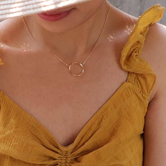 Model wearing gold circle necklace that hits on collarbone 