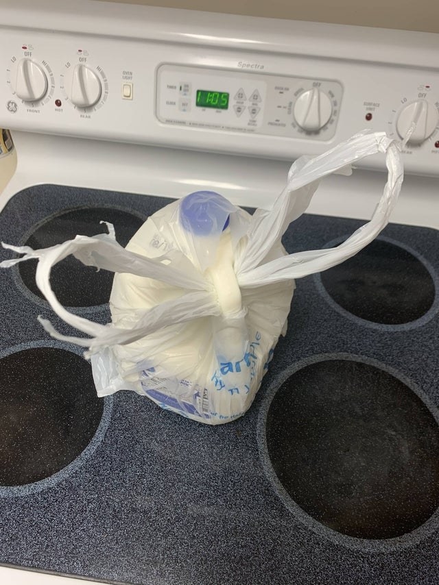 A milk jug with a plastic bag tied underneath the handle.