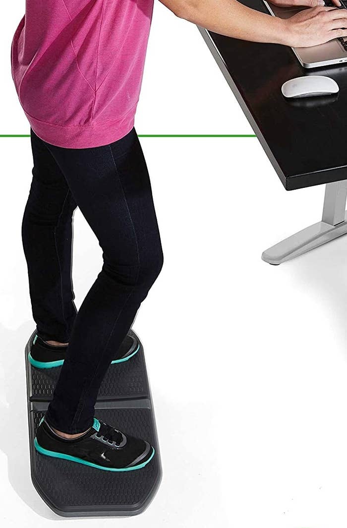 A model standing on the flat balance board as they work on their computer