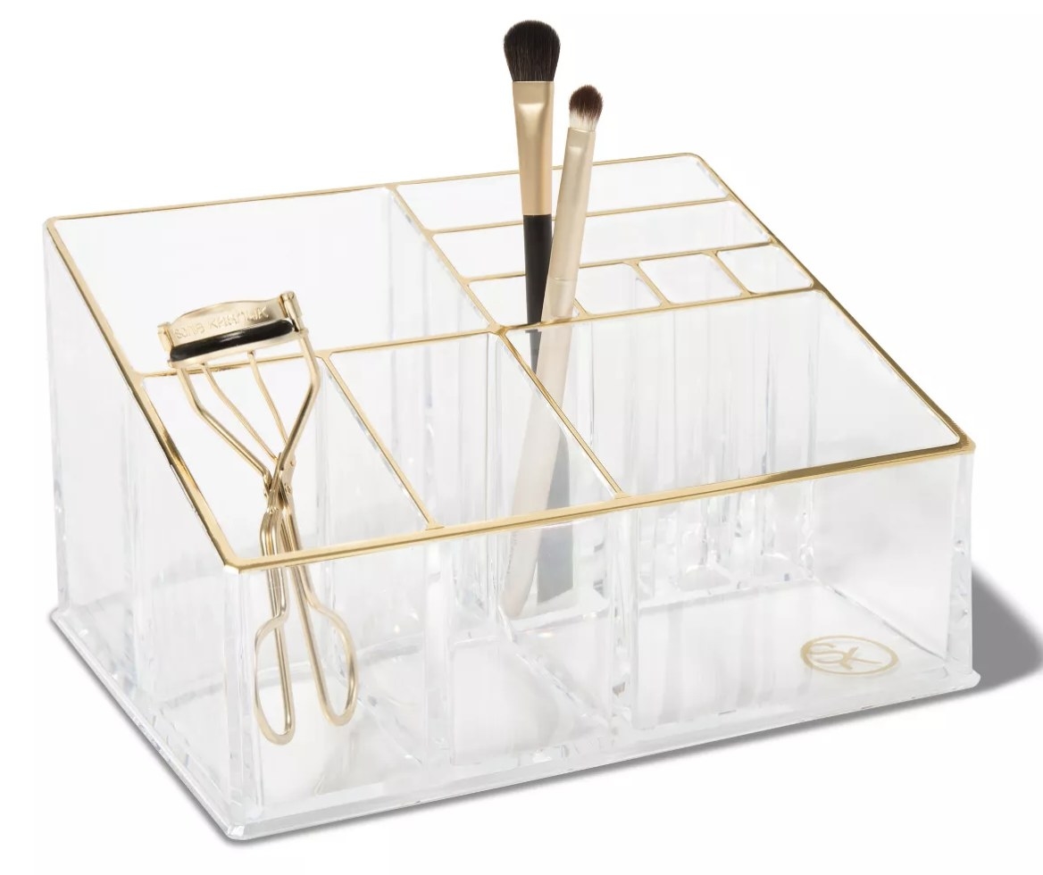 The clear organizer featuring an eyelash curler and makeup brushes