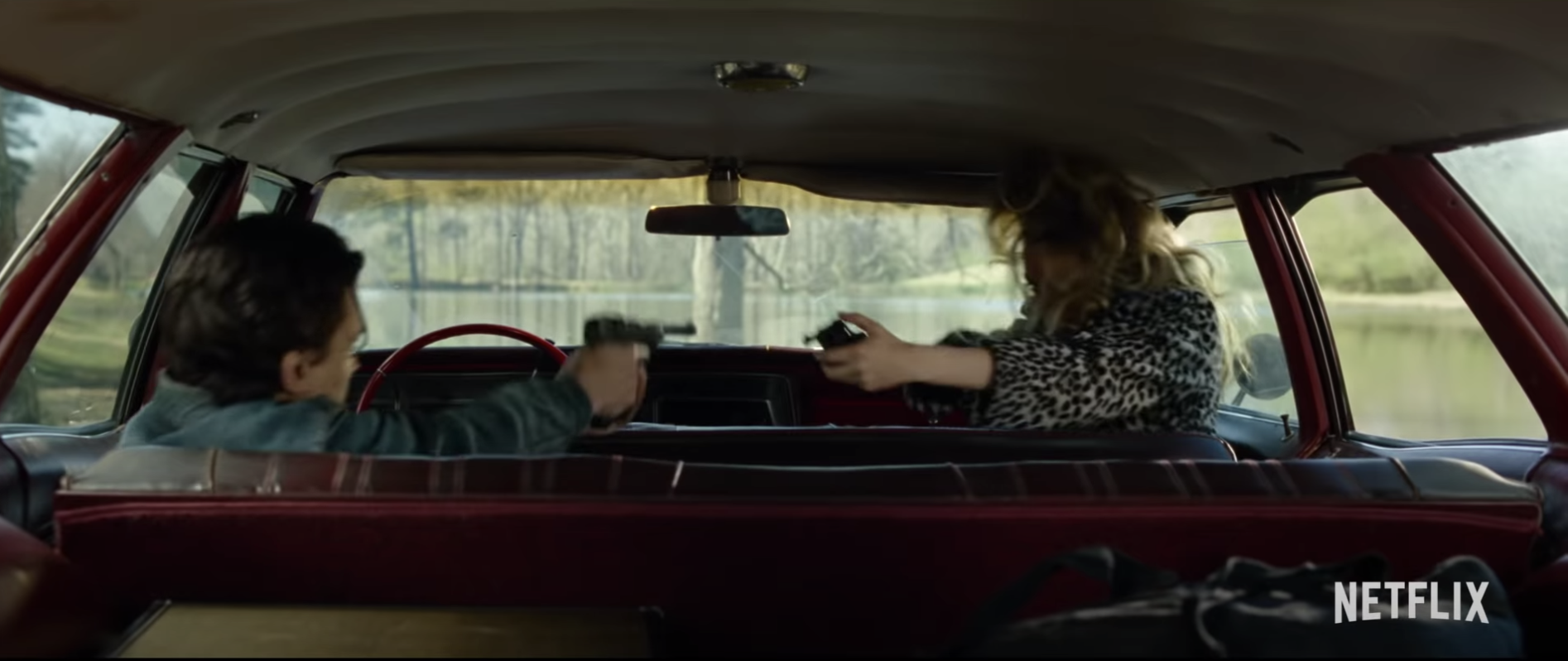 Arvin (Tom Holland) and an unidentified female pointing a gun at one another in Arvin&#x27;s car in &quot;The Devil All The Time.&quot; 
