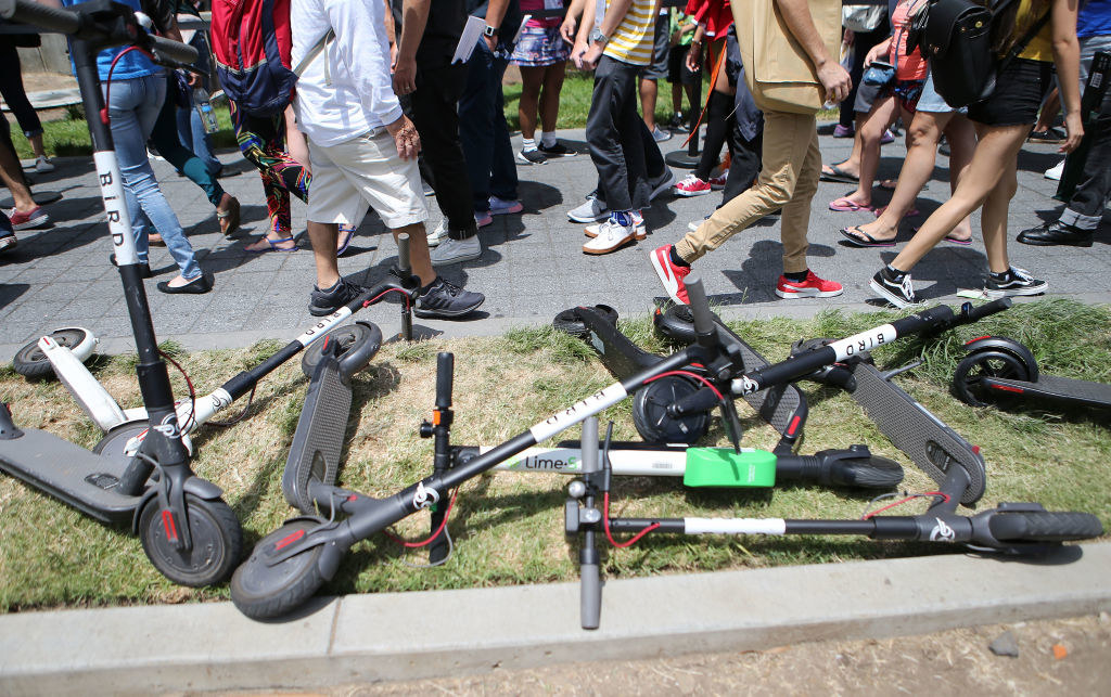 Pile of electronic scooters laying on a sidewalk