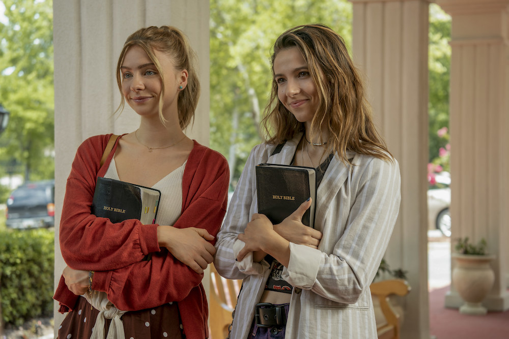 Two teenage girls smile smugly while holding bibles.