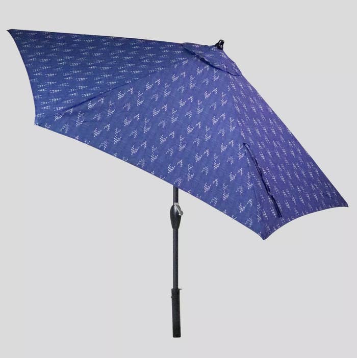 A large, blue patio umbrella with a white arrow pattern tilted to the side 