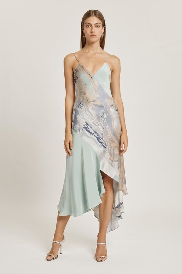 A model in an asymmetric light blue and marble print midi slip dress