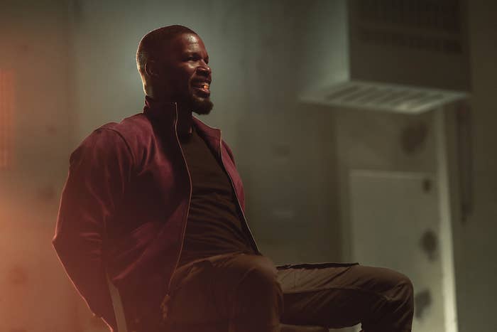 Jamie Foxx sits in a chair with his hands tied up and a flowing pill in his mouth. From the movie Project Power.