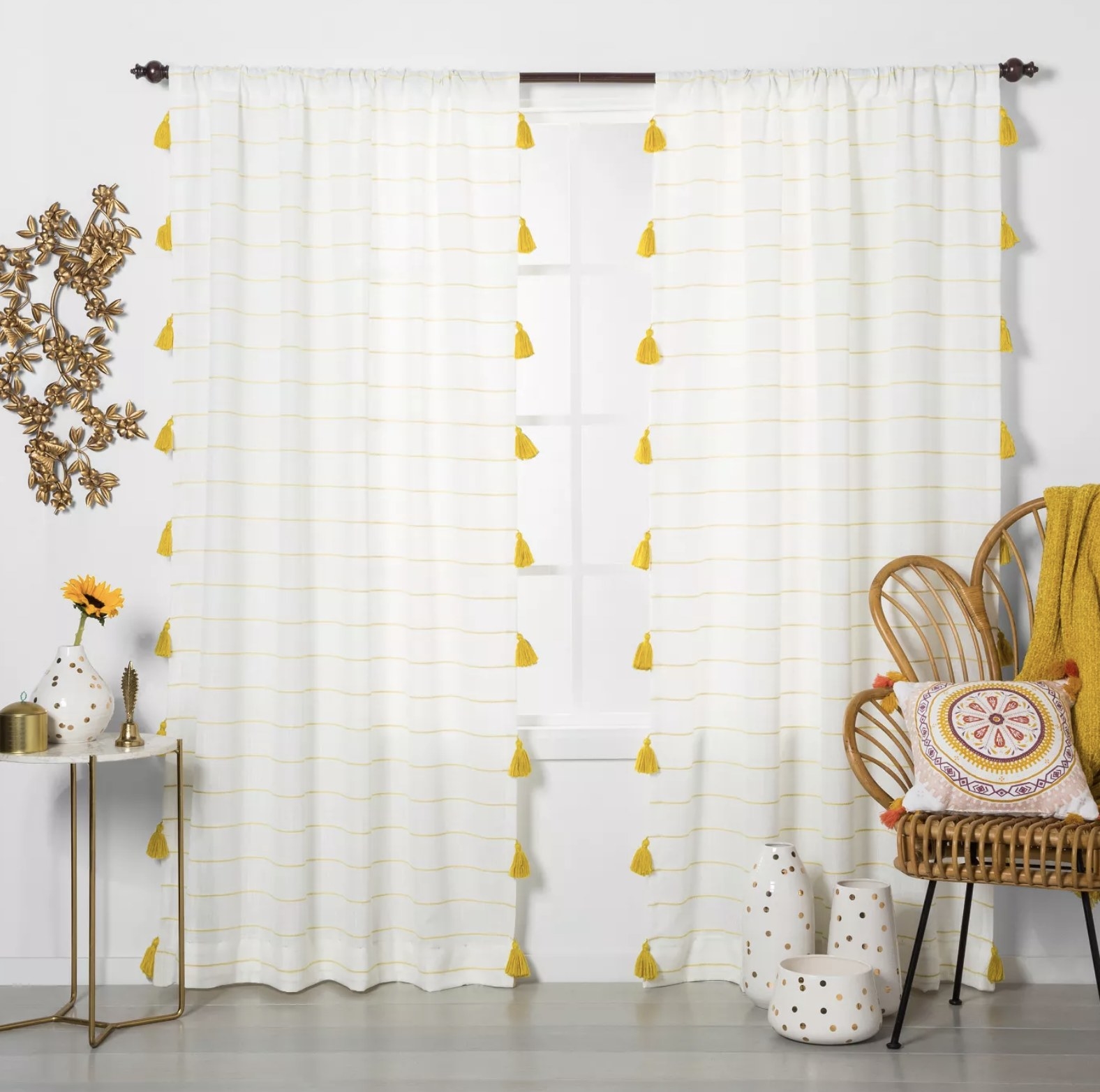 The white curtains with yellow tassels displayed on a window