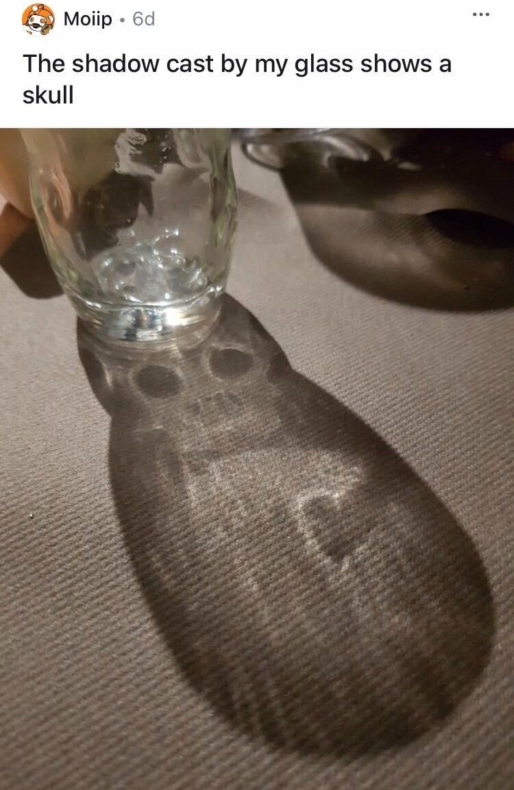 A glass is casting a shadow that has a creepy skull in it
