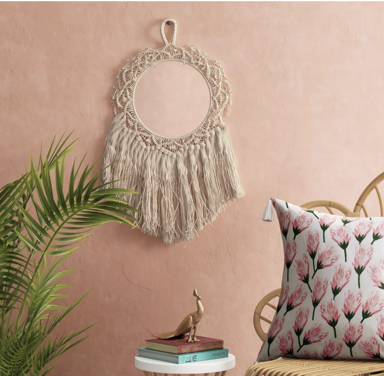 Macrame wall hang placed on pink wall above a chair, side table and plant