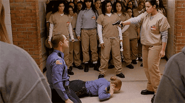 Daya threatening the guards with a gun while the other inmates watch