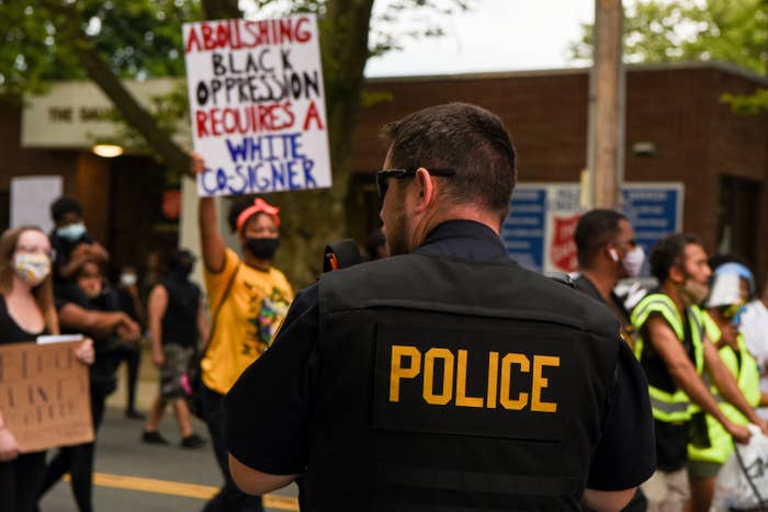Signs carried by protesters include one reading "Abolishing black oppression requires a white co-signer."
