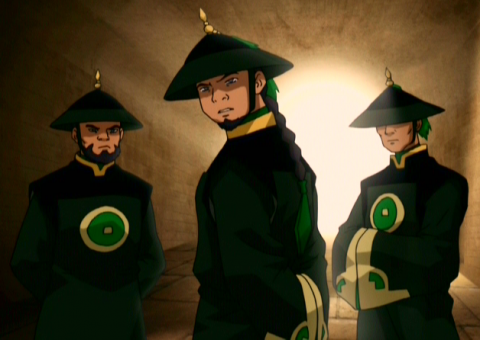 Three members of the Dai Li; they are dressed in long, emerald green robes and pointed hats