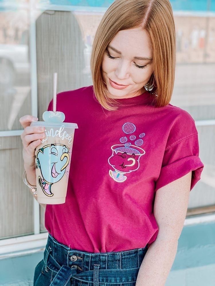 A model holding a tumbler with a straw emblazoned with their name and Chip from &quot;Beauty and the Beast&quot;