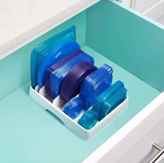 A drawer organizer with food container lids sorted by size and shape