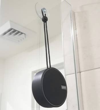 Reviewer image of the black speaker hanging from a suction cup in a shower 