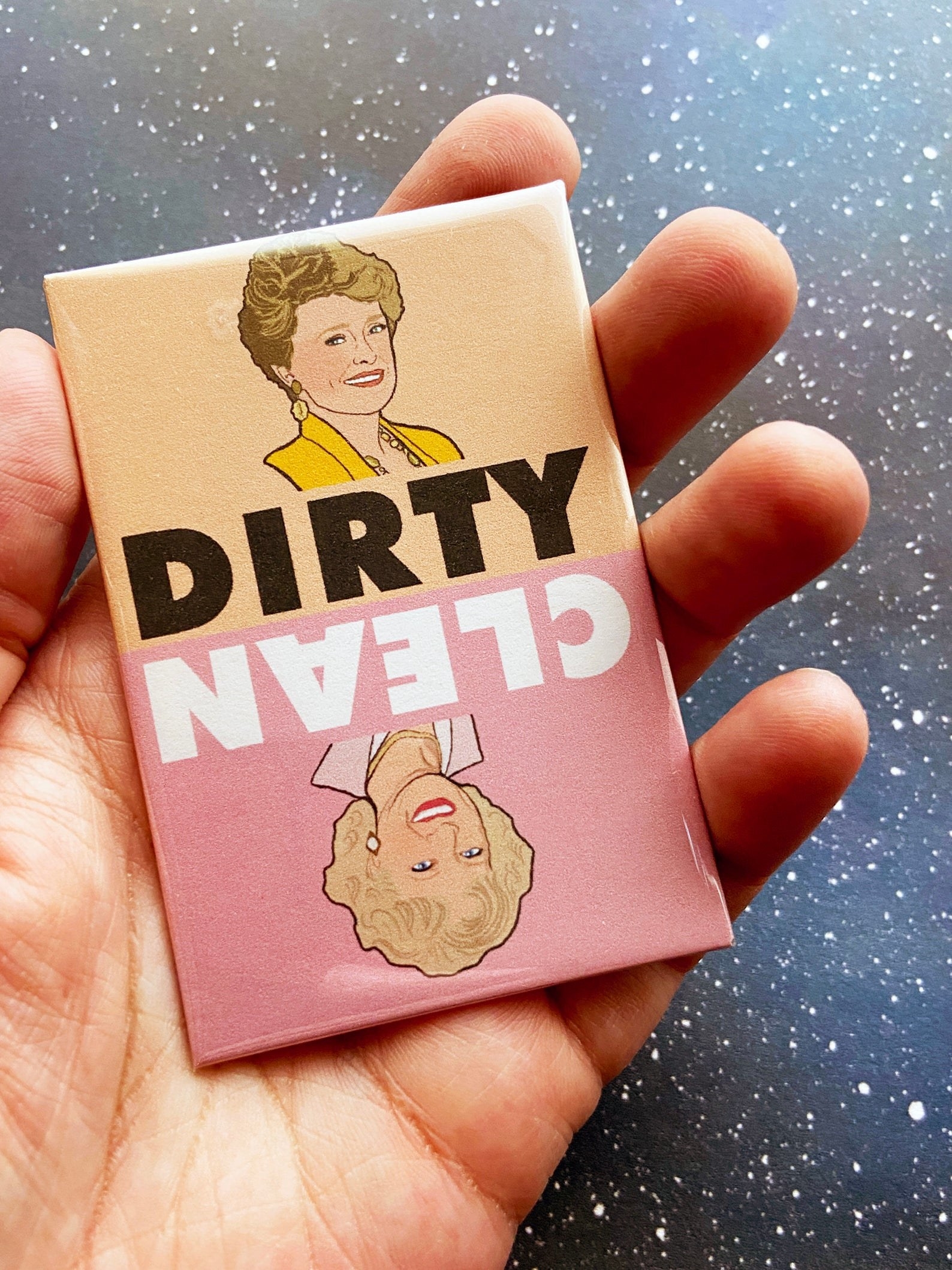 hand holding a golden girls magnet that says clean with an illustration of blanche on one side that says &quot;dirty&quot; and rose on the other side that says &quot;clean&quot;
