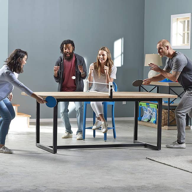 Models playing ping pong on a table with the net installed on it 