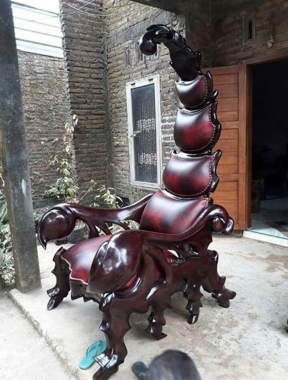 A chair shaped like a scorpion&#x27;s body, with pincer arm rests and a curved tail for back support