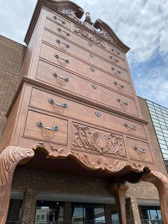 A structure has a building-sized dresser in front of it