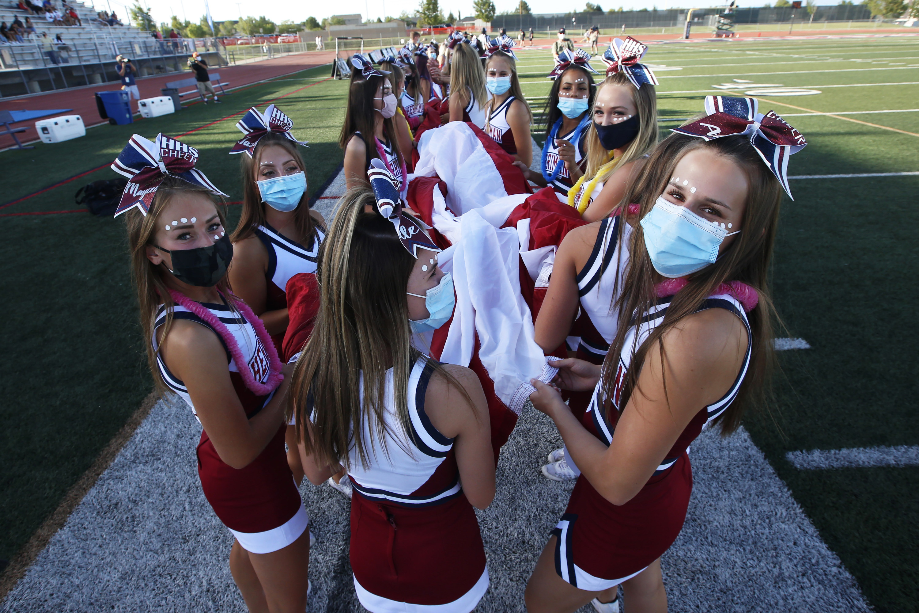 Herriman cheerleaders carry the American flag before the start of a high sc...