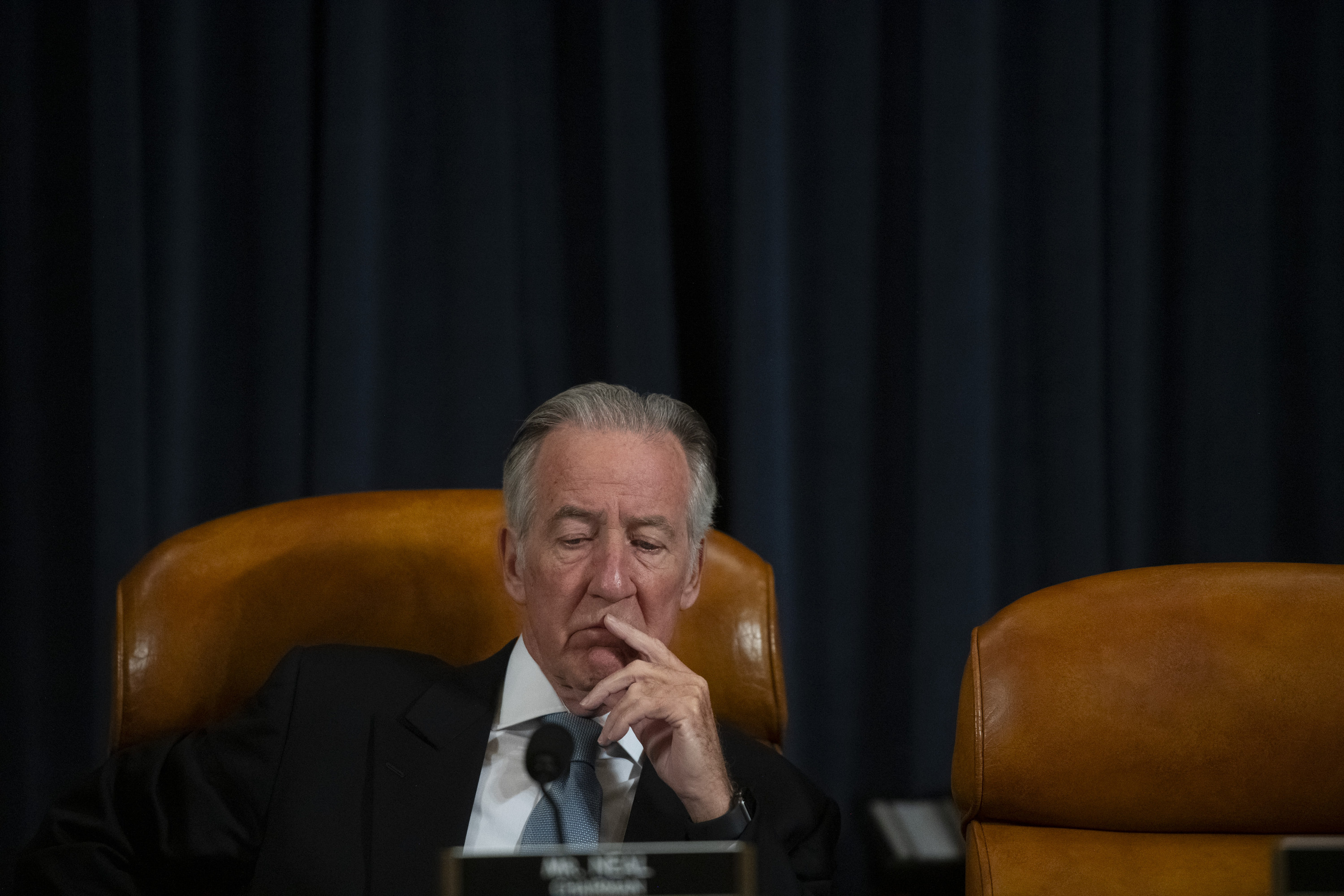 Richard Neal sits on a leather chair with his hand to his face during a congressional committee meeting