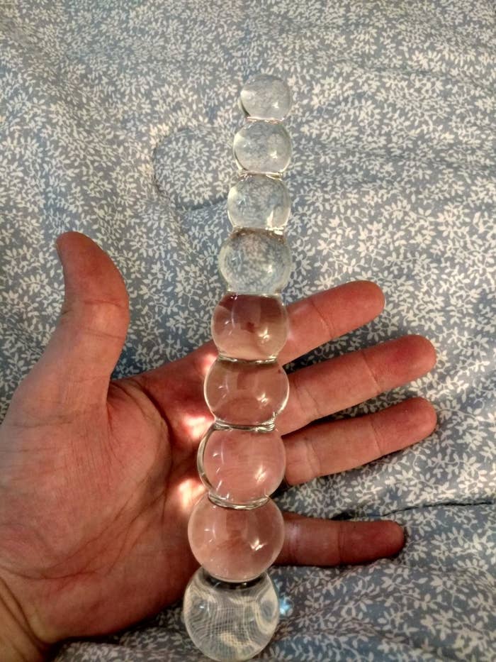 Reviewer holding the icicle-shaped glass dildo