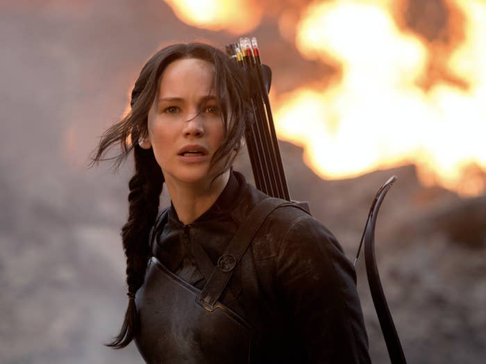 Katniss with her bow and arrows with a fire behind her