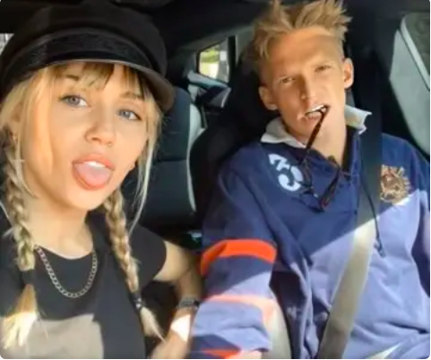 Miley and Cody sticking their tongues out while driving in a car