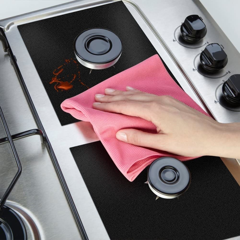 A person wiping down the burner covers with a microfibre cloth