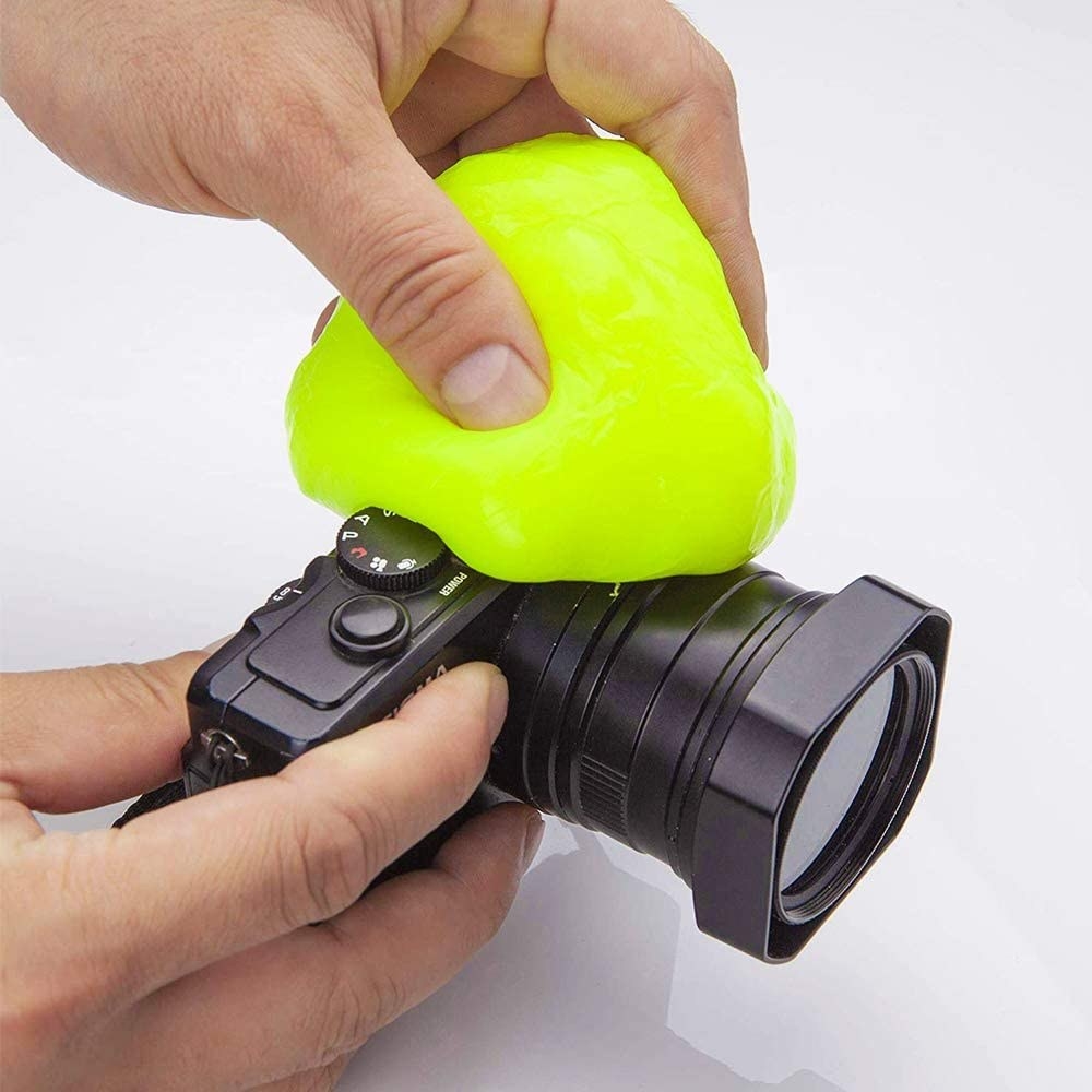 A person using the cleaning slime to clean their camera
